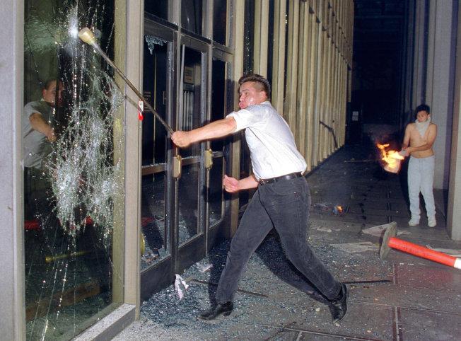 A rioter breaks a glass door of the Criminal Courts building in downtown Los Angeles on April 29, 1992.